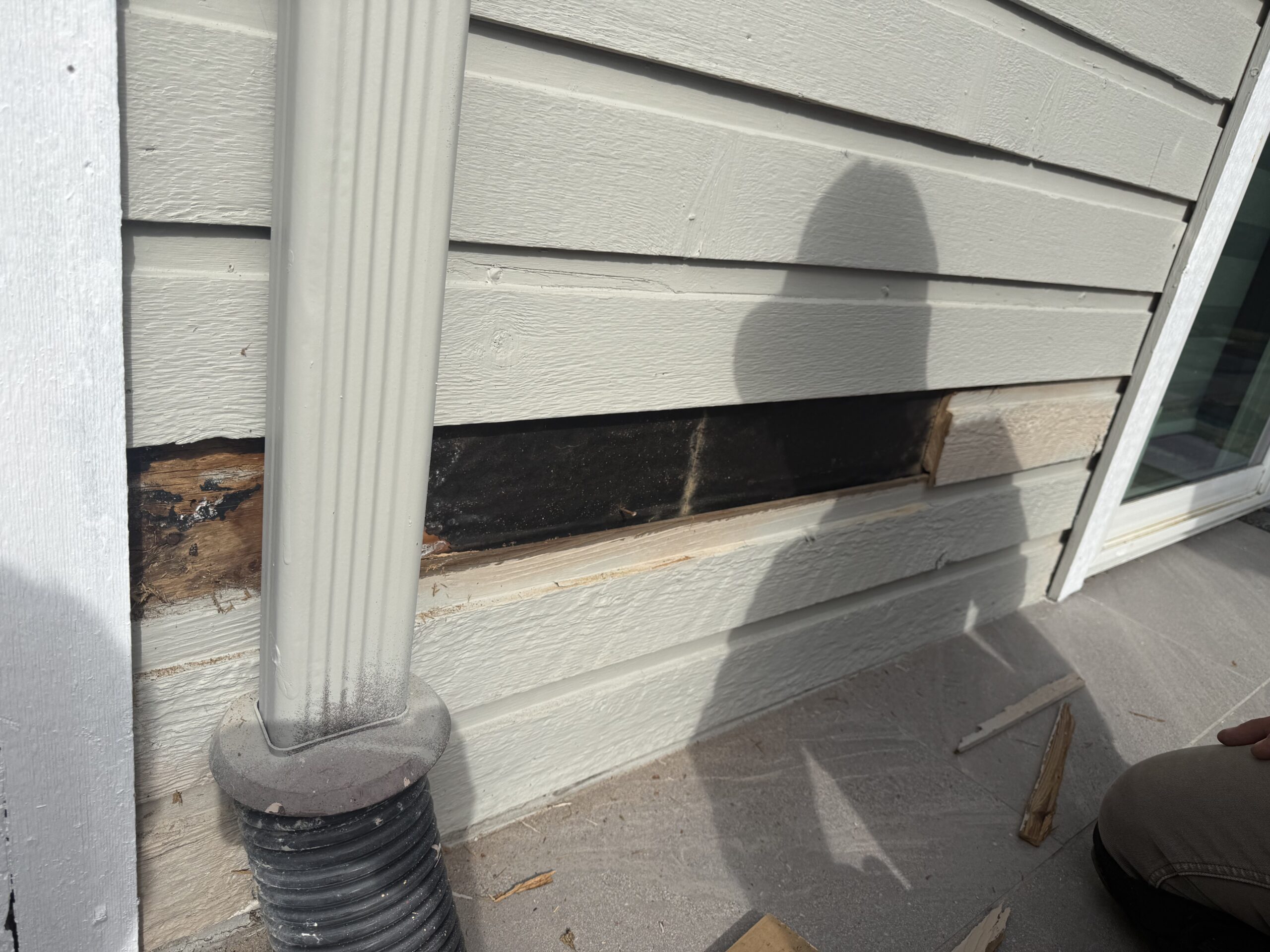 Damaged exterior wood siding with exposed wood underneath