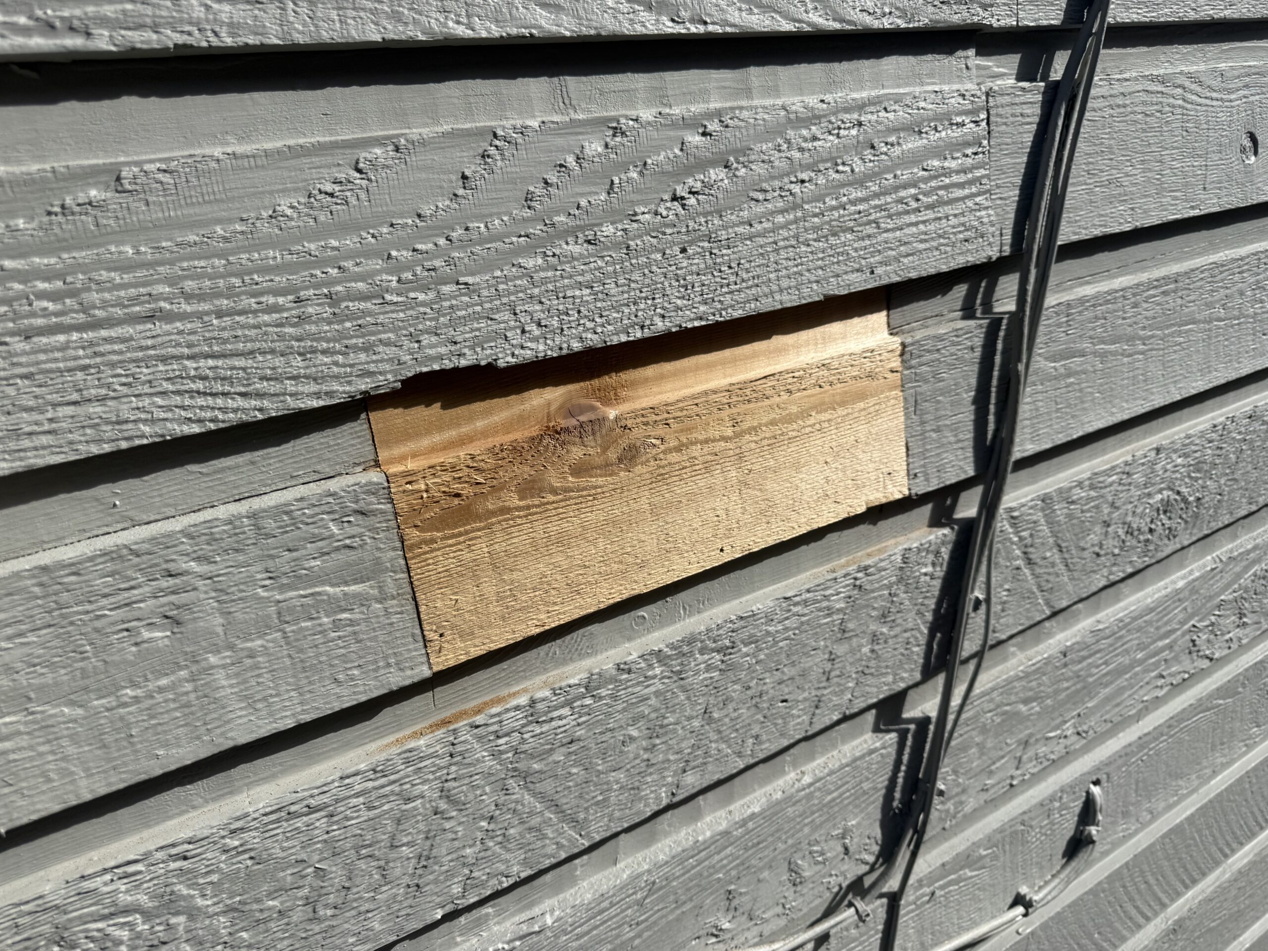 Close-up of replacement wood installed in exterior siding