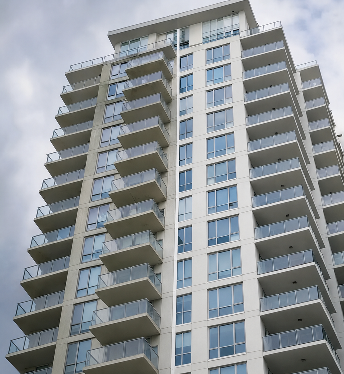 High-rise residential tower with glass balconies, viewed from below